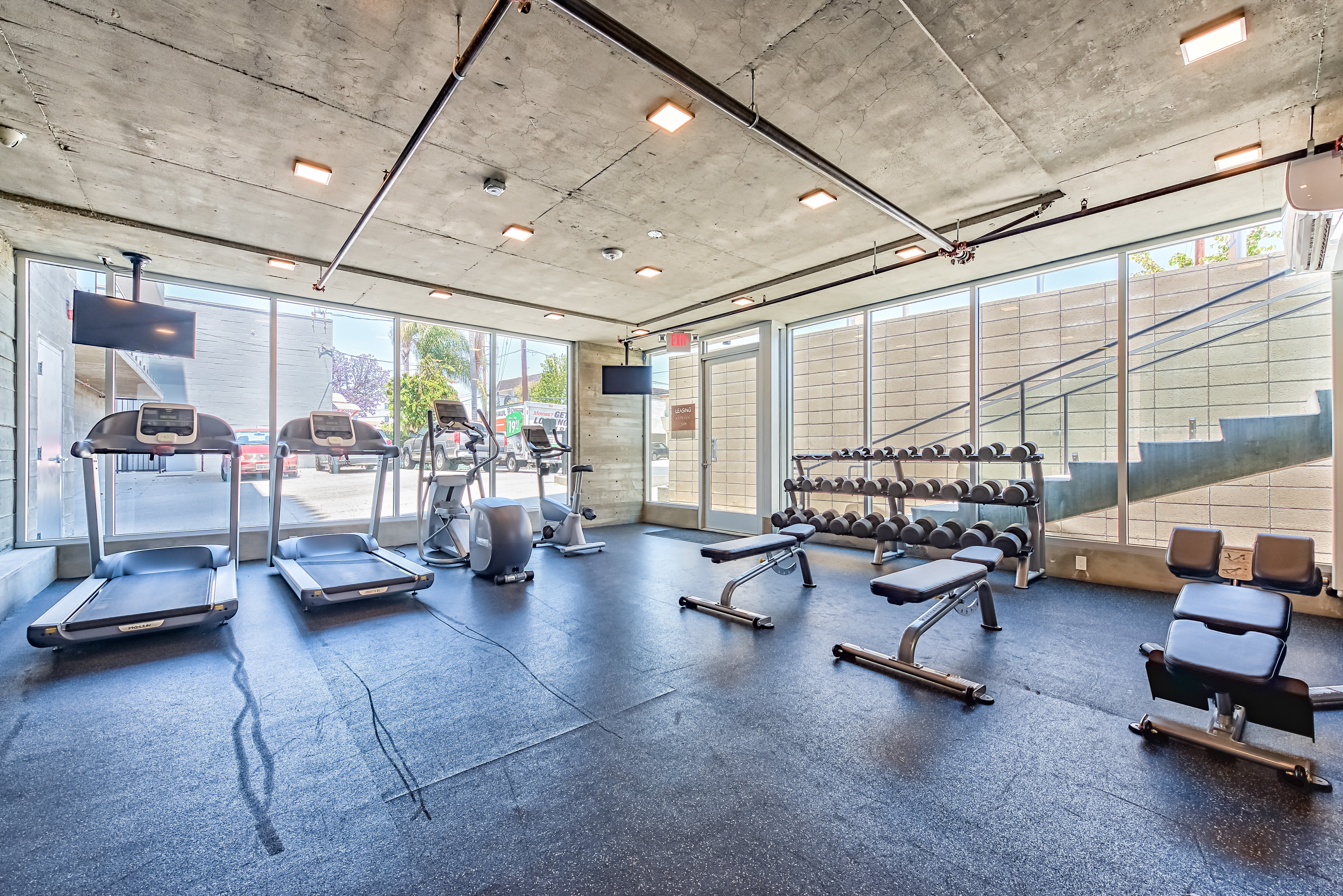 A gym with treadmills, exercise bikes, and weight benches.